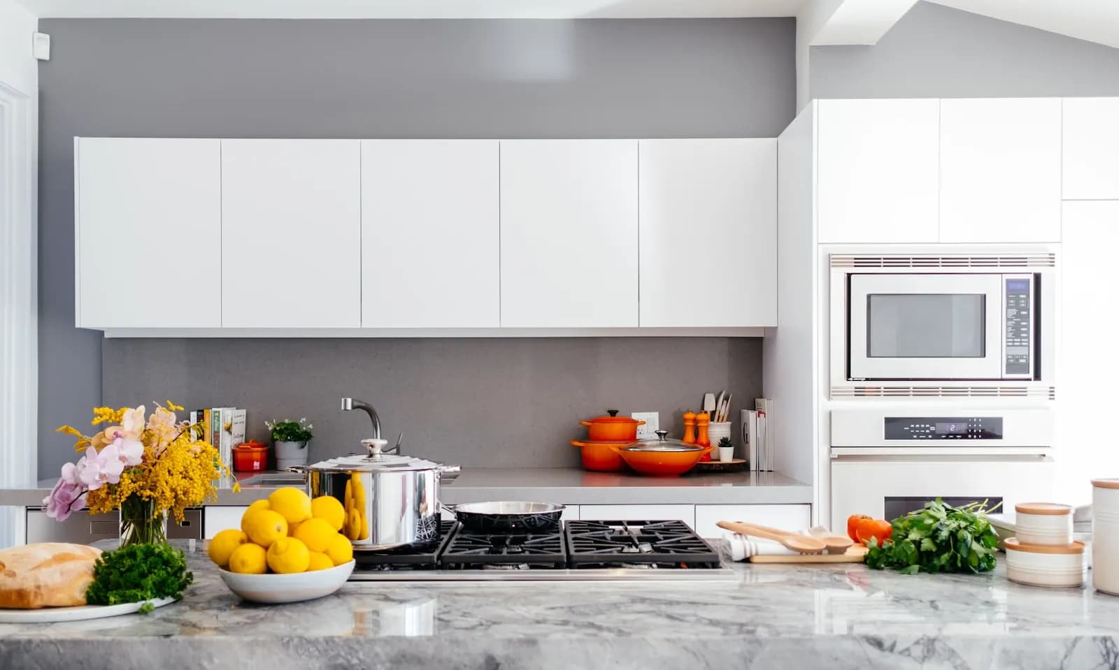 Cuisine équipée aux façades blanches, avec four encastré et plaque de cuisson